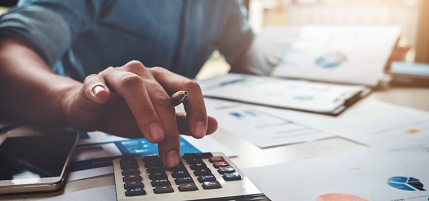 Person is sitting next to a desk and calculating on a calculator