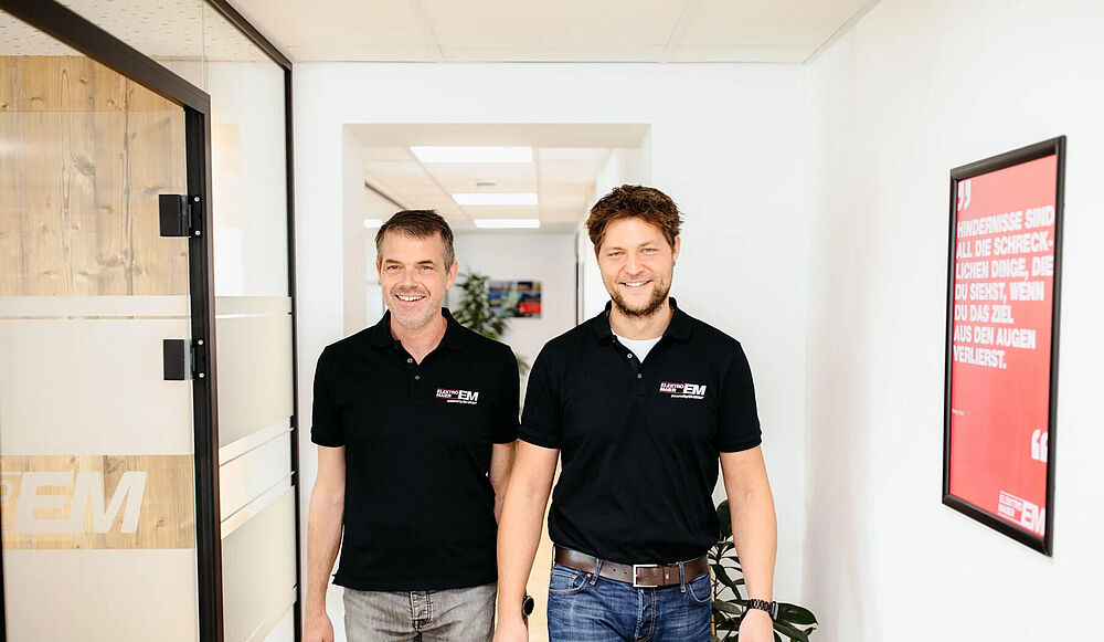 Zwei Männer stehen mittig in schwarzen Elektro-Maier T-Shirts